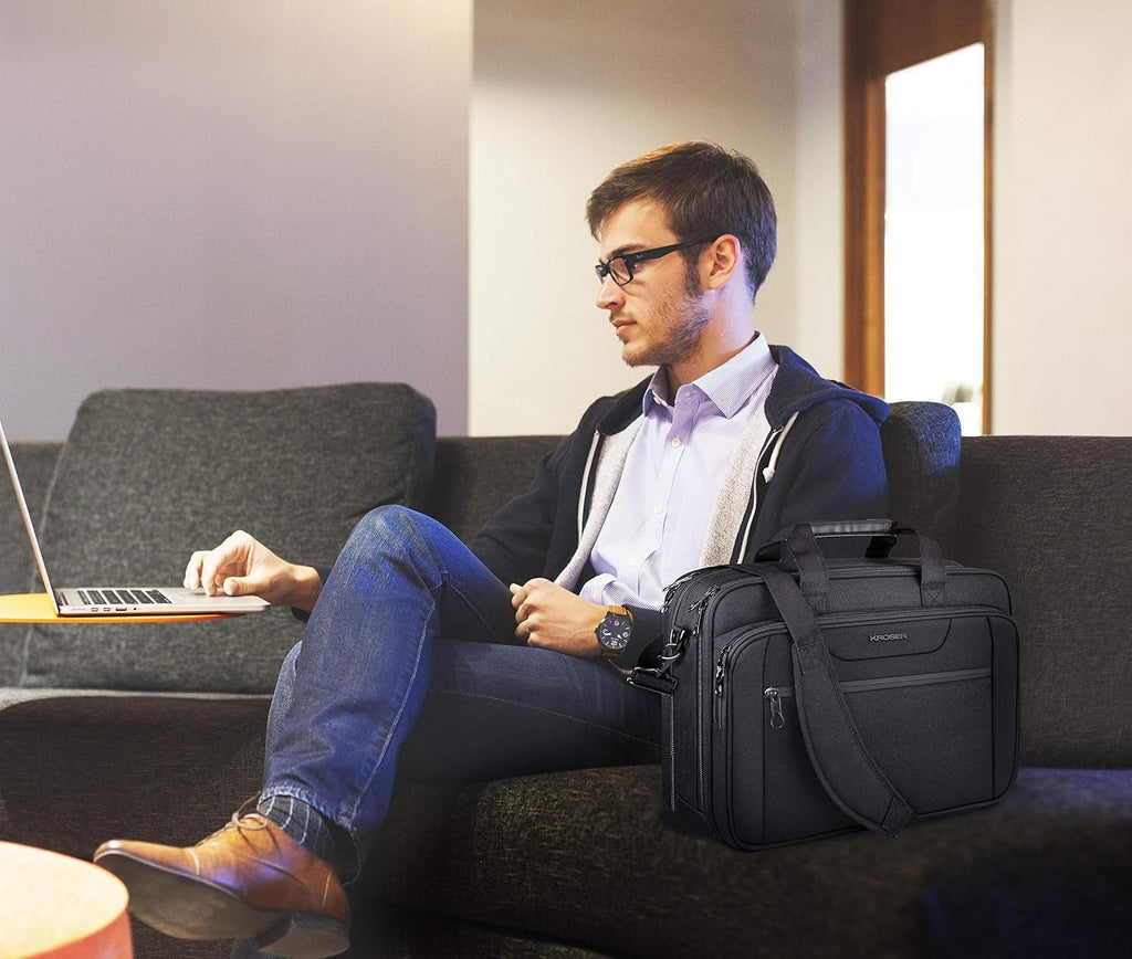 Black laptop briefcase carried at lap with shoulder strap on seated traveler.