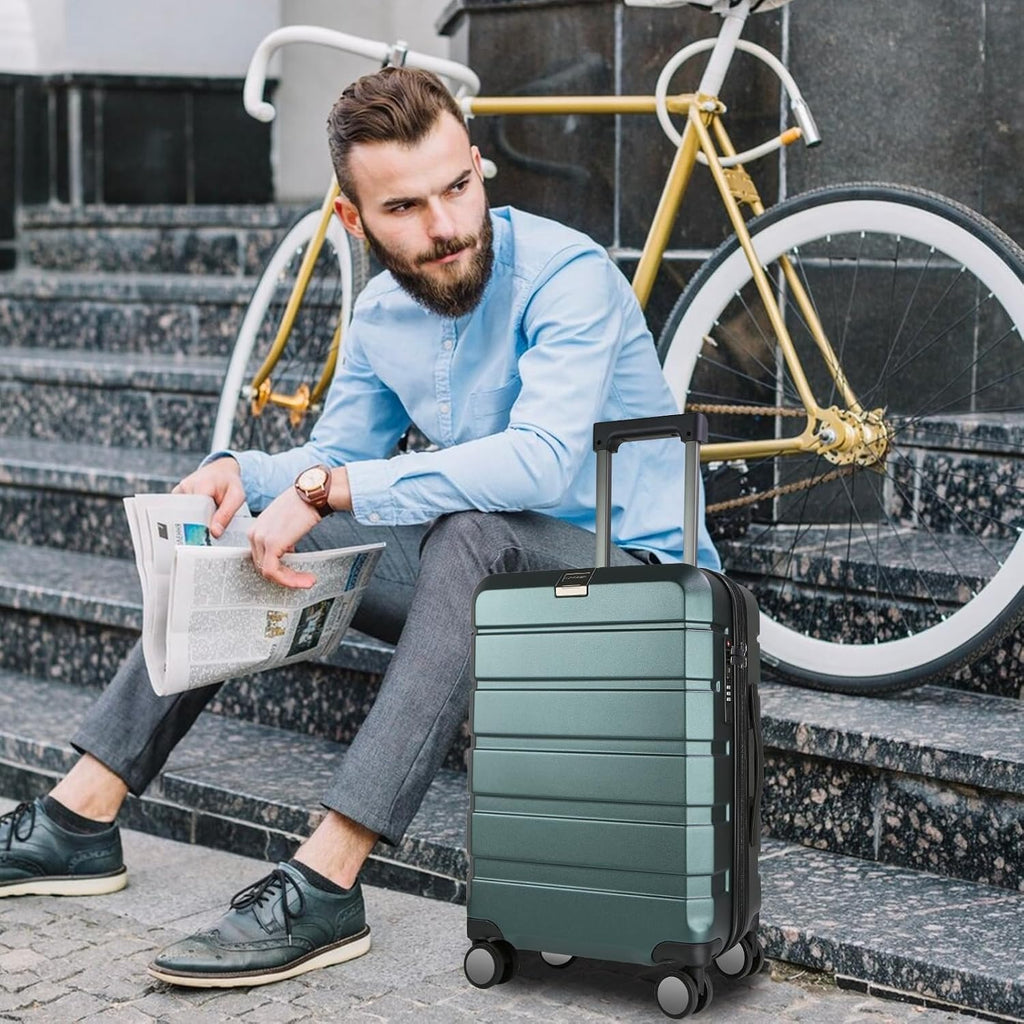 Dark green hardside carry-on suitcase on wheels beside a seated traveler
