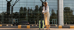 Green carry-on luggage with telescoping handle and four wheels, shown in use outdoors